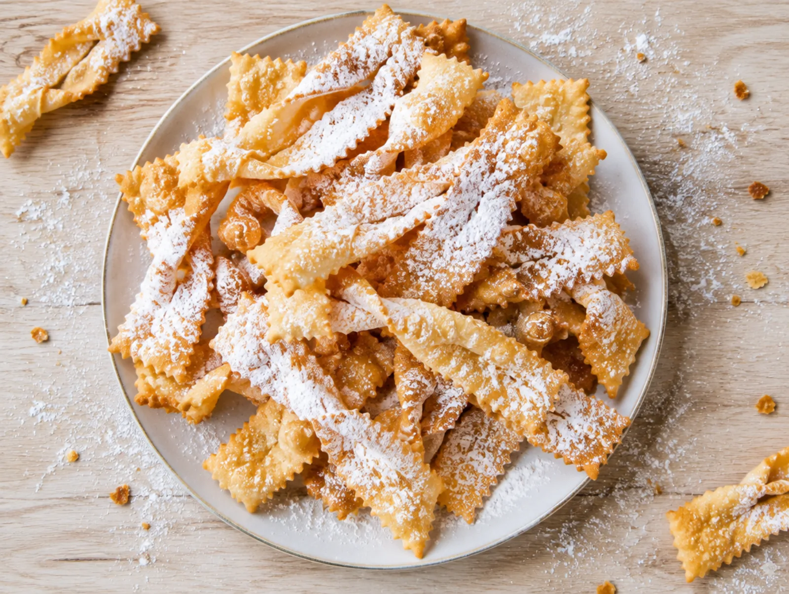 Chiacchiere met poedersuiker en sinaasappelschil op een bord